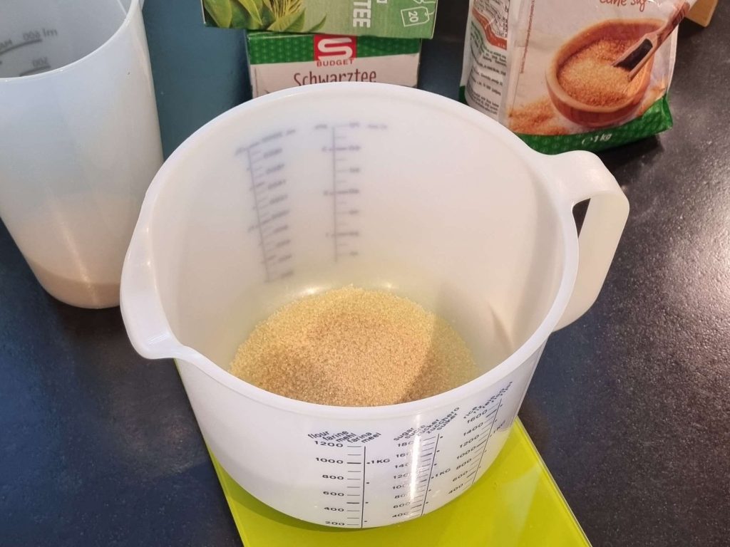 Close up of a measuring cup filled with sugar for kombucha fermentation