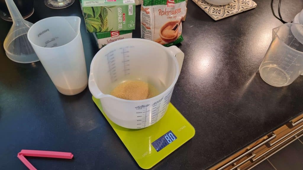 Measuring sugar on a kitchen scale for homemade kombucha recipe