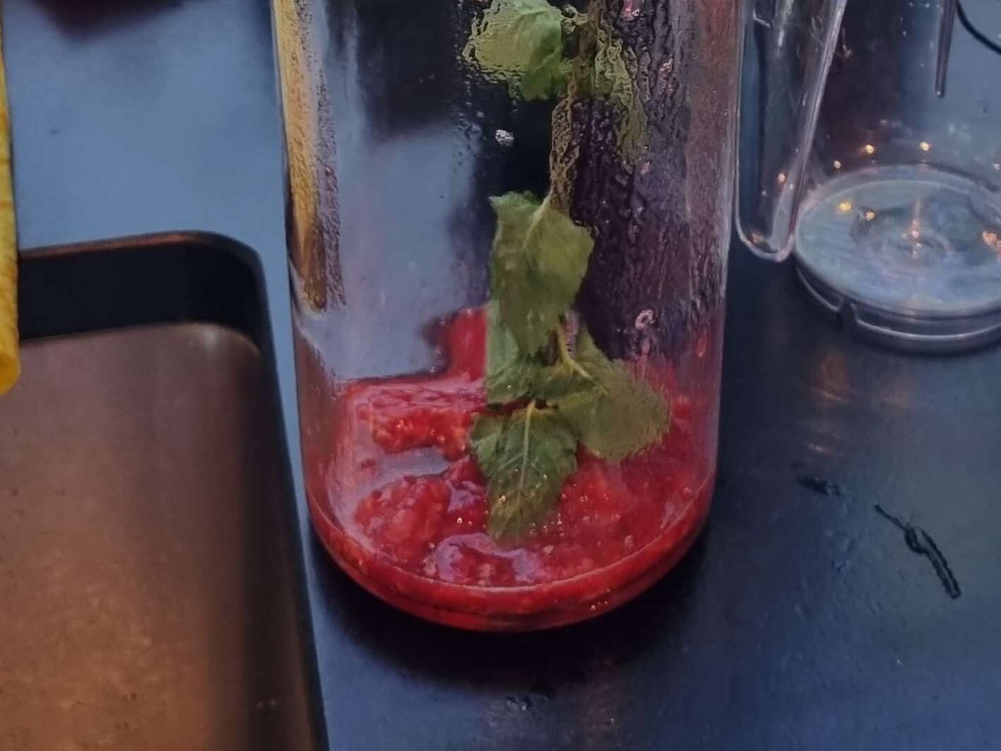 Pouring homemade kombucha from brewing jar into glass bottles for second ferment with raspberry mint