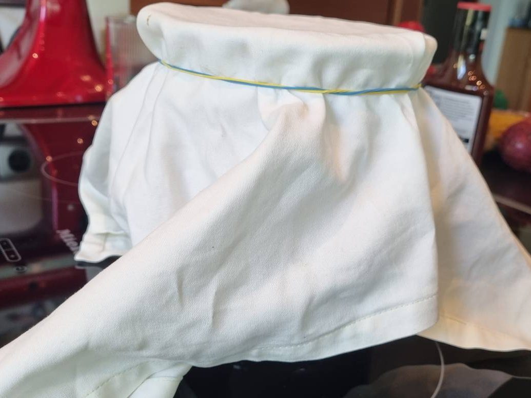 Kombucha jar covered with tightly woven cloth secured with rubber band during first fermentation