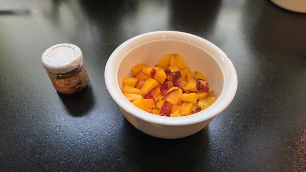 Fresh nectarine cut into pieces in a bowl and vanilla powder